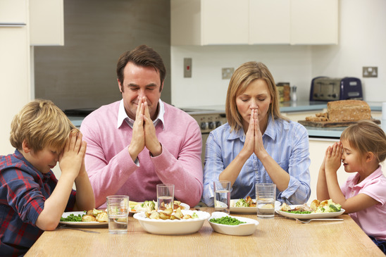 Family saying grace before dinner