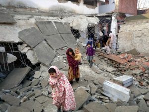 Children walk on the debris of a damaged school building after it was blown up by the Taliban in Swat Valley