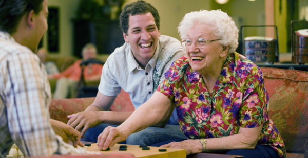 elderly woman playing checkers with young men