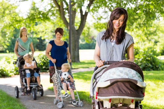 Three women walking their young children in a park
