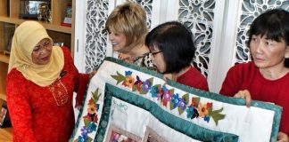 Women leaders in Malaysia present a quilt as a token of appreciation to the minister of women, family, and community development.