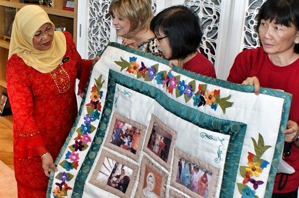 Women leaders in Malaysia present a quilt as a token of appreciation to the minister of women, family, and community development.