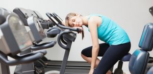 Woman asleep on stationary bike at the gym