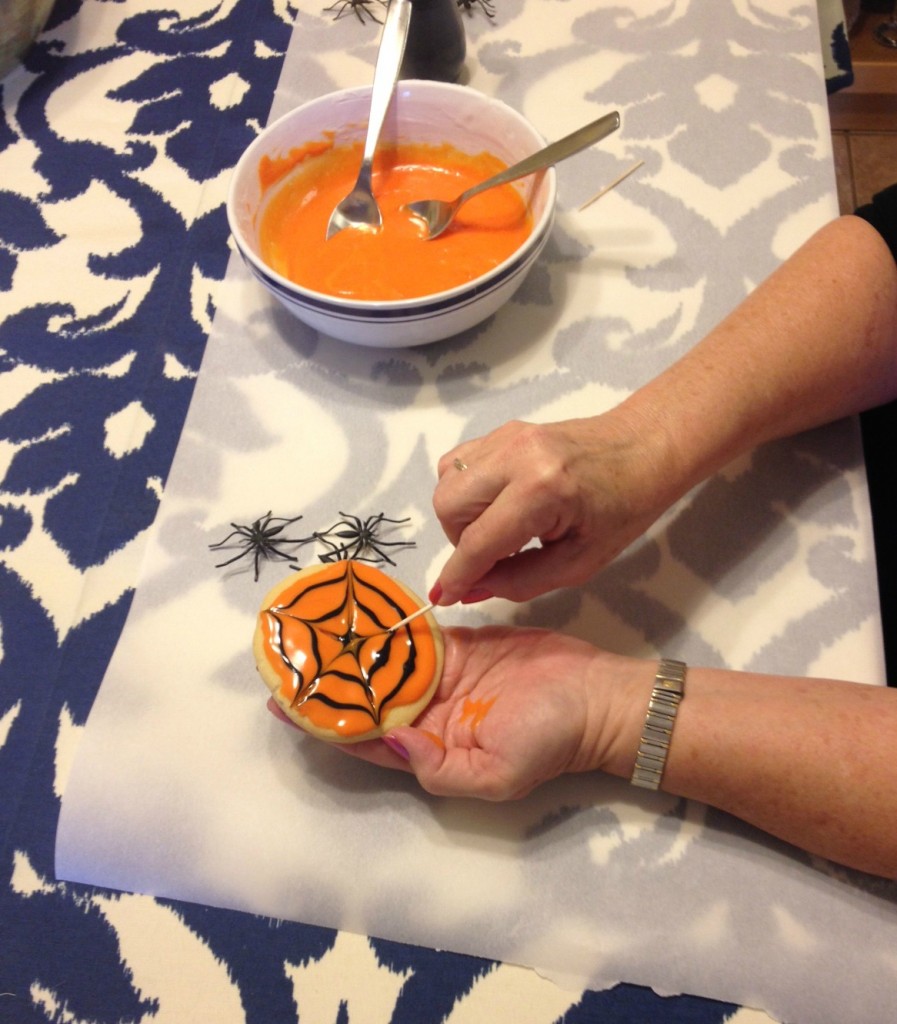 Using a toothpick on cookie icing to create a spider web design