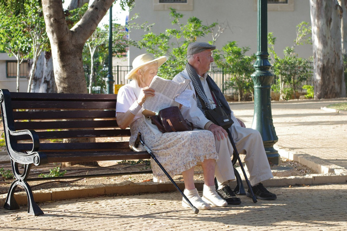 Happy elderly couple sit on a park bench