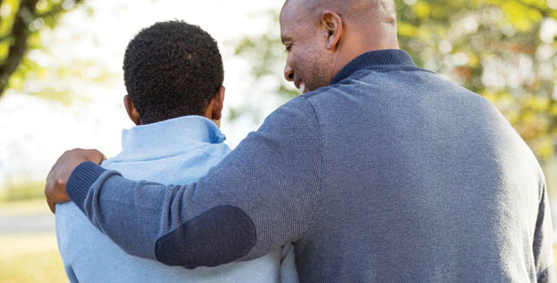 Father puts his arm around son to support him