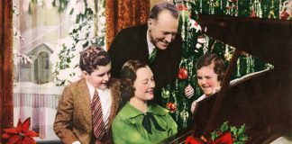 Family gathered around piano singing Christmas songs