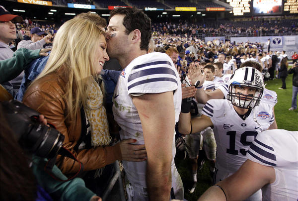 BYU football player embraces wife on field sideline