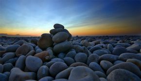 photo of stacked stones in front of a sun rise