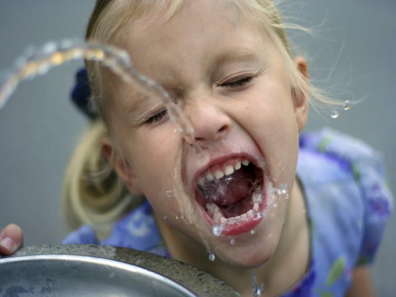 Little girl drinking water from a water fountain