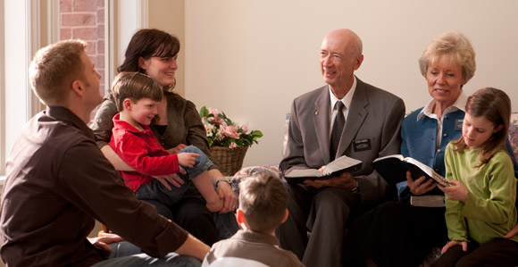 “Senior missionary couple teaching a young family the gospel”