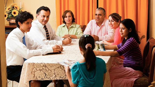 A family gathered around a table being taught