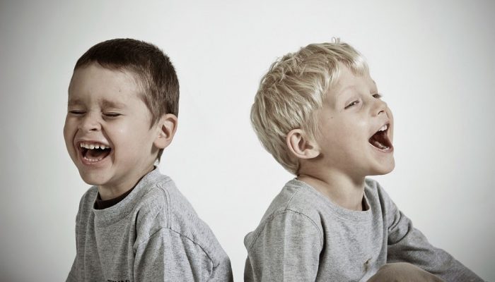 Two boys sitting by each other laughing