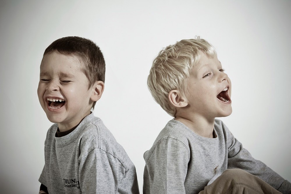 Two boys sitting by each other laughing