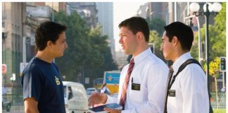 Two male Mormon missionaries talking with a young man on the street