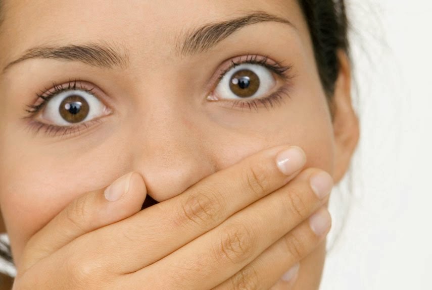 Woman covering her mouth with her hand with a surprised look on her face.