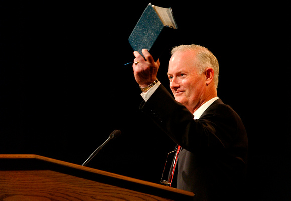 Former BYU-Idaho president Kim. B Clark holding up scriptures at a BYU-Idaho Tuesday devotional