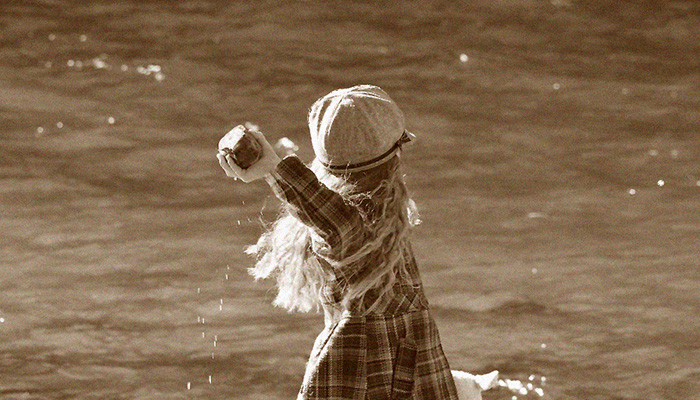 A girl throws a rock into a pond