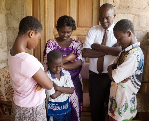 Family kneeling in prayer to dedicate their home