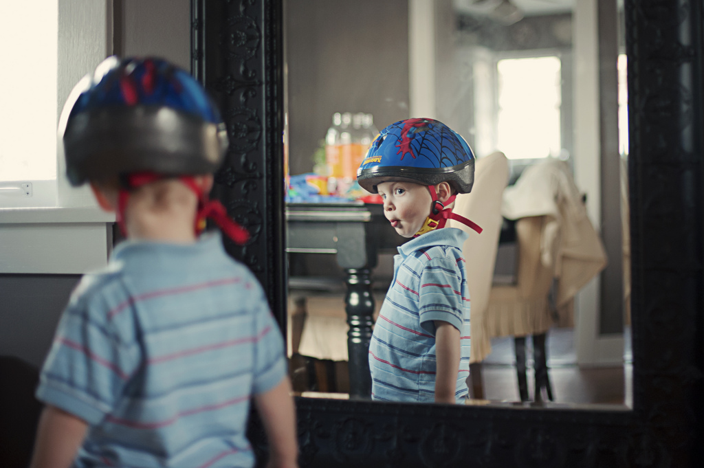 Kid in bicycle helmet poses in mirror