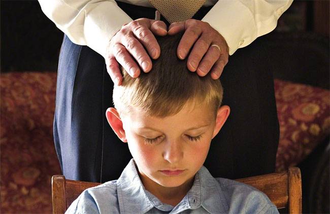 A Father gives a priesthood blessing to his son