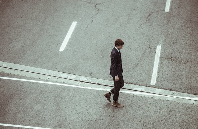 Sad man in a suit walking on sidewalk