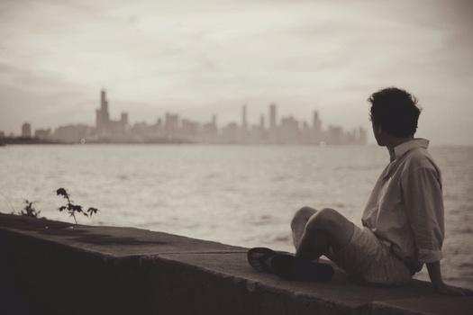 Man sitting by himself looking at a city.