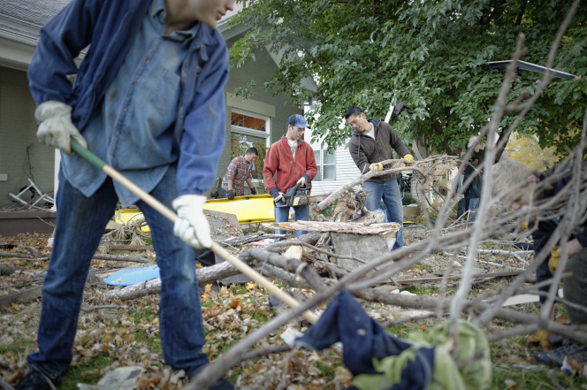 Father and sons cleaning up fallen trees during service project