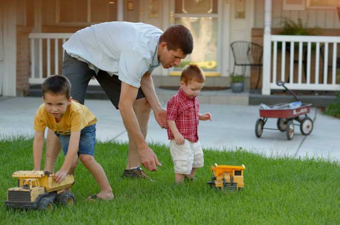 A dad playing trucks with sons