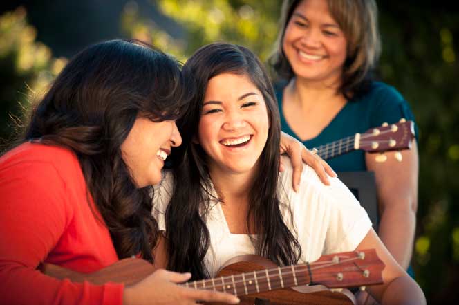 Visiting Teachers playing ukuleles with a sister of their ward