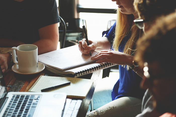 A group of people sitting down and working on a project.