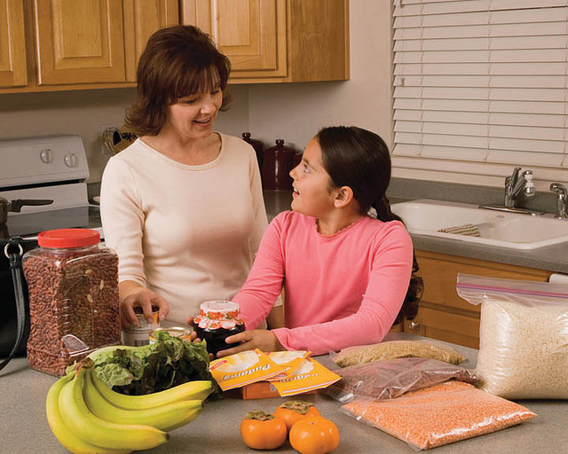 Girl helping mother in kitchen