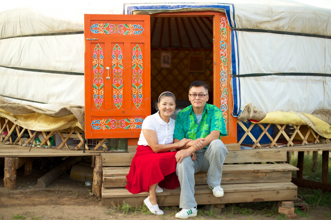 Mongolian couple sitting in front of their yurt