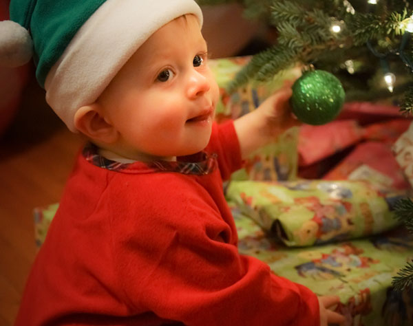 Child waits by presents in Santa Hat