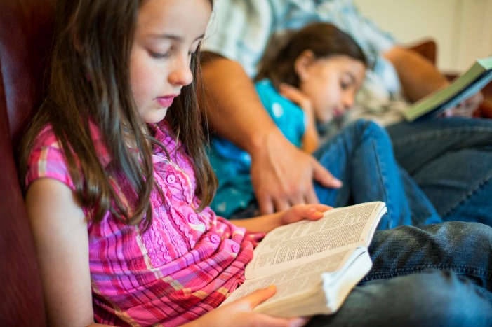 girl reads scriptures with family