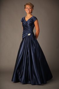 A woman wears a floor-length navy prom dress.