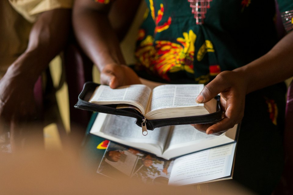 A woman holds open a set of scriptures in her hands.