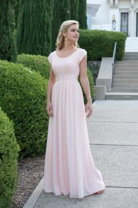 A woman wears a floor-length pink prom dress.