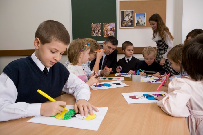 A primary teacher colors with his students