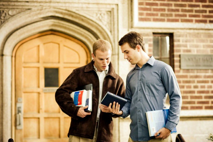 A college student shows his friend a Book of Mormon.