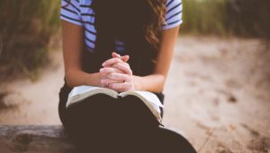 girl praying with scriptures in her lap