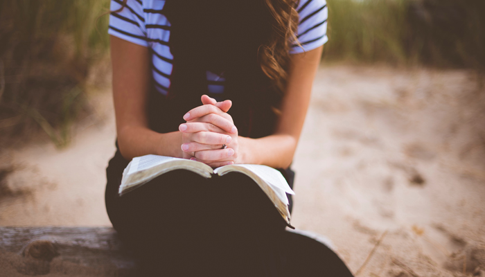 girl praying with scriptures in her lap