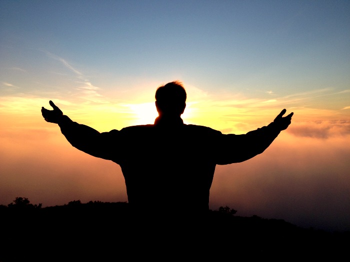 Man with his arms spread out surveying a sunrise