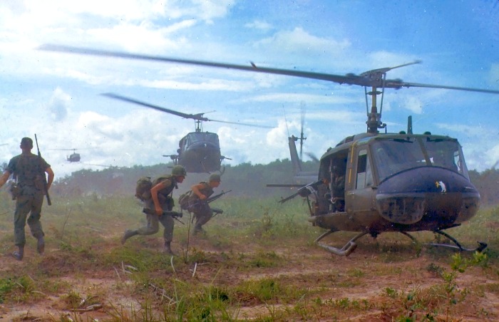 Vietnam War Helicopter with Soldiers being evacuated in a grass field.