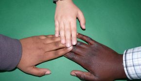 three hands of various races touching