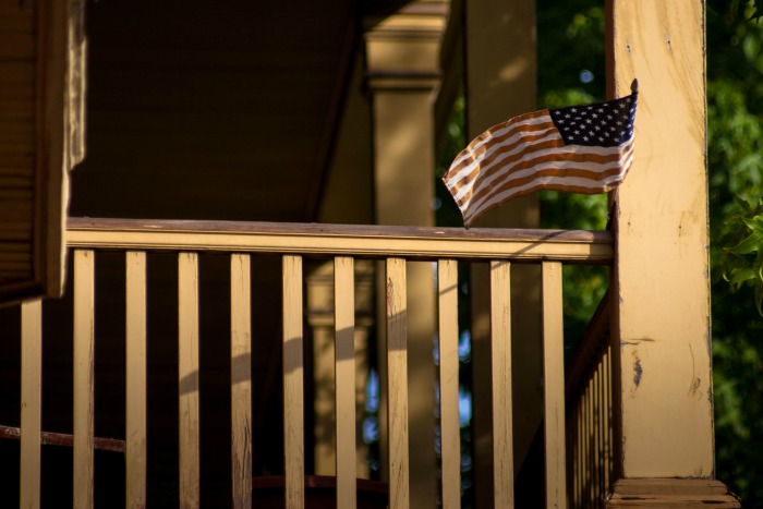 House porch flanked by American Flag