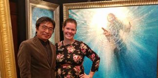 Katie Garner and Yongsung Kim pose in front of Kim's large-scale painting entitles "The Hand of God."