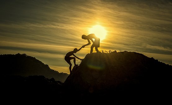 one person helping another climb a hill