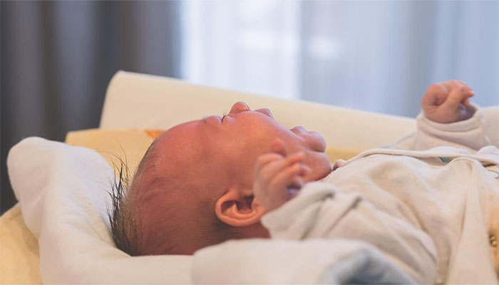 Baby cries on hospital bed