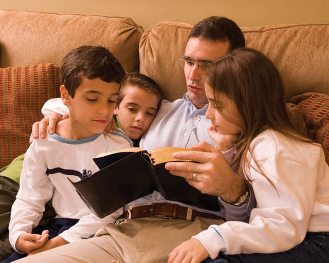 Mormon father reading scriptures to children